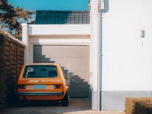 Eine Garage an einem Haus und davor steht ein orangefarbenes Auto