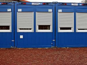 Blaue Baucontainer mit grauen Rollläden an den Fenstern