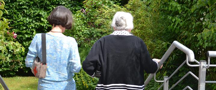 Zwei Frauen gehen eine Treppe hinunter in eine Gartenanlage