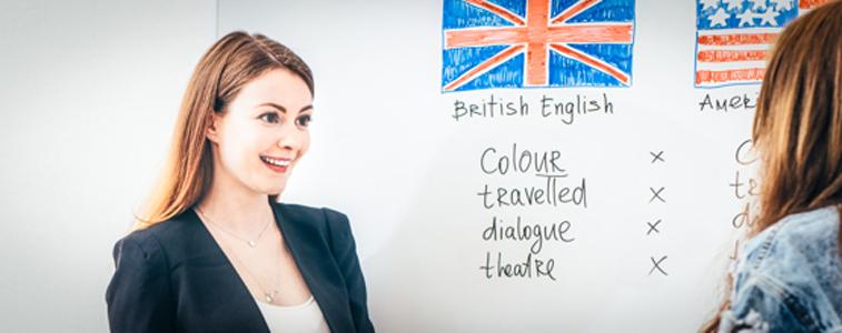 Eine Frau steht vor einem Whiteboard an dem die Britische und die Amerikanische Flagge aufgemalt ist