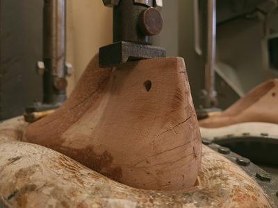 Ein Stück Holz wird bearbeitet um eine Schuhvorlage zu erstellen