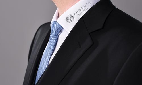 Schulter und Brust-Foto, auf den Kragen des weißen Hemds ist das Logo von Phoenix Security