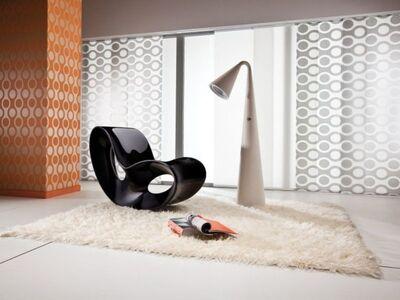 Vorhänge in einem Raum mit einem weißen Teppich und einem schwarzen Stuhl und einer Stehlampe