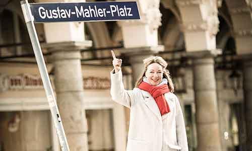 Angelika Franke steht vor dem Straßenschild vom Gustav-Mahler-Platz