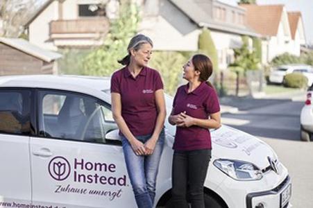 Zwei Frauen stehen vor einem weißten Auto mit HomeInstead Logo