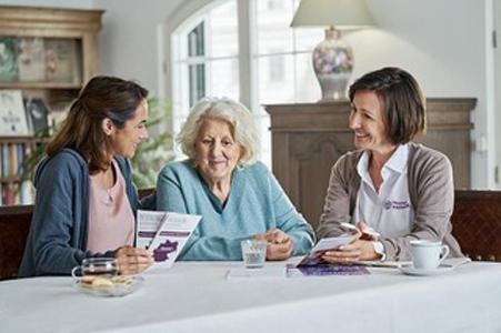 Drei Frauen sitzen an einem Tisch und sprechen miteinander