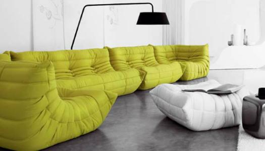 Ein gelbes Sofa mit einer schwarzen Lampe dahinter