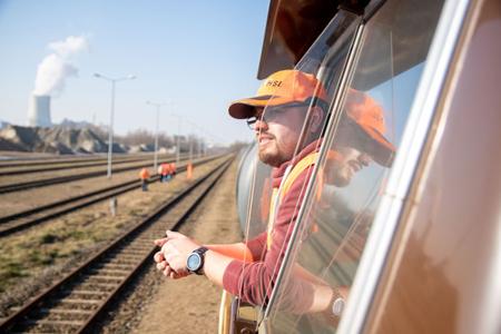 Ein Mensch in einem Zug, schaut aus dem Fenster auf die Gleise