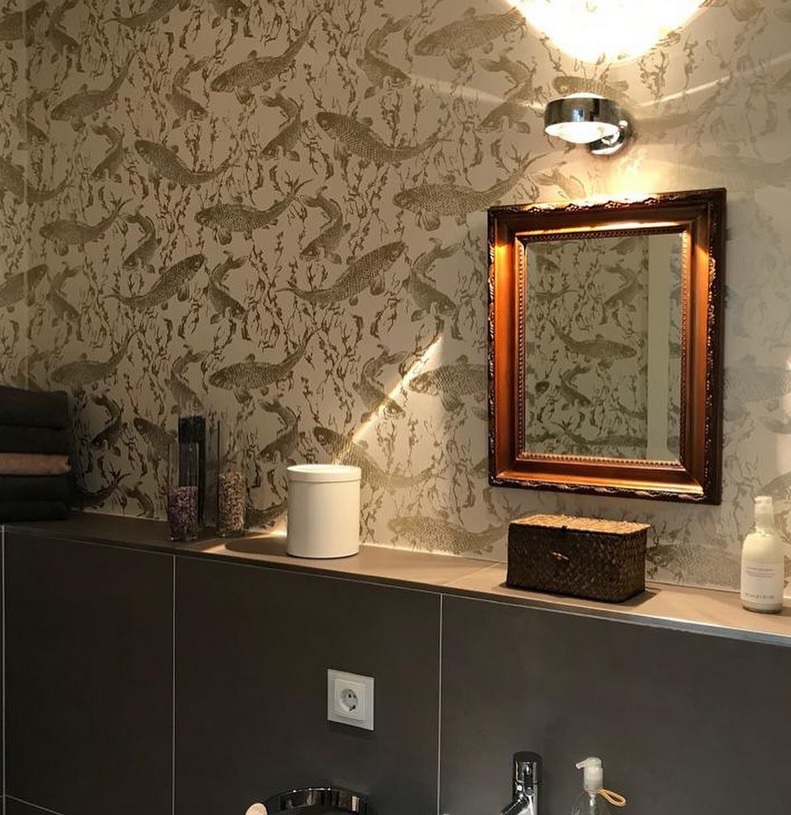 Eine Kommode und darüber ein Spiegel an der Wand mit gemusterter Tapete