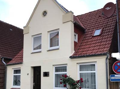 Eine weiße Fassade eines Hauses mit weißen Fensterrahmen und einem roten Dach