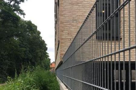 Ein Zaun trennt ein Gebäude von einer Wiese