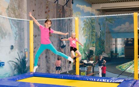 Kinder springen auf blaugelben Trampolinen