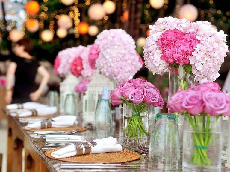 Gedeckter Tisch mit rosa Blumen in einer Eventlocation.