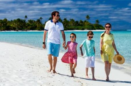 Vier Menschen an einem Strand mit türkisfarbenem Wasser