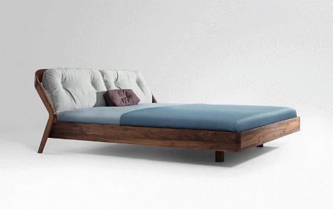 Ein Bett aus dunklem Hol mit einem blauen Bezug