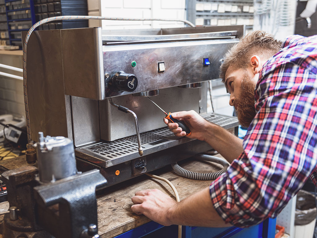 Handwerker repariert Kaffeevollautomaten