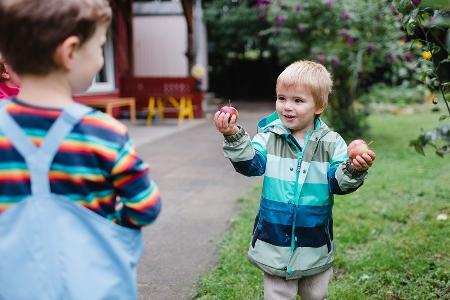 Ein Kind hält zwei Äpfel in der Hand