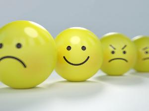 Vier gelbe Bälle mit unterschiedlichen Gesichtsausdrücken im Smileydesign