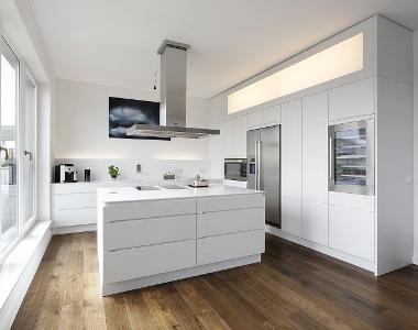 Eine weiße Küche mit freistehender Mittelkonsole und einem Holzfußboden