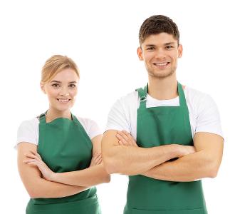 Ein Mann und eine Frau stehen nebeneinander, haben beide ein weißes TShirt an und eine grüne Schürze darüber