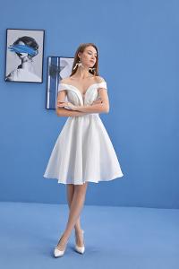 Frau im weißen Kleid vor blauer Wand