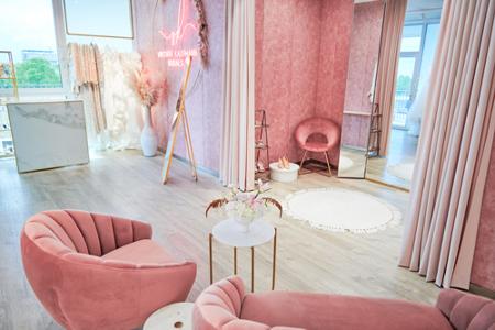 Zwei rosafarbene Sessel vor einer Umkleide mit einem großen Spiegel
