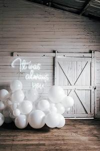 Weiße Luftballons und ein weißer Schriftzug an einer weißen Holzwand it was always you