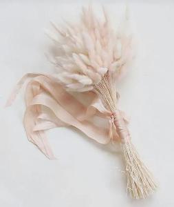 Ein Brautstrauß aus hellen Trockenblumen und einem rosefarbenen Seidenband