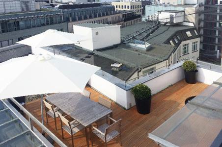 Eine Dachterrasse mit weißen Sonnenschirmen und hellbrauner Terrasse