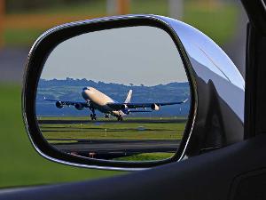 Ein Autospiegel in dem man ein startendes Flugzeug sieht