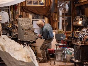 Ein Bildhauer in seiner Werkstatt bei der Arbeit an einer Skulptur