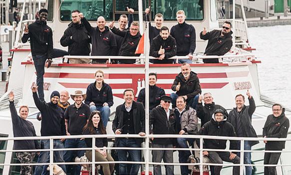 Das Team von Barkassen-Meyer Touristik GmbH & Co. KG steht auf einer Barkasse