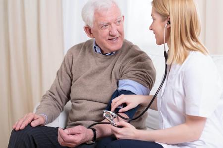Eine Ärztin misst bei einem älteren Herren den Blutdruck