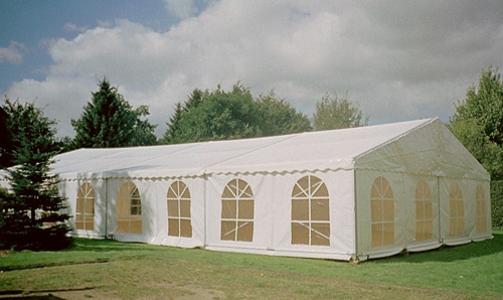 Ein weißes, großes Zelt auf einer grünen Wiese mit Aussparungen in Fensterform