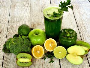 Grünes Gemüse und Obst sowie ein grünes Getränk auf einem Holzfußboden