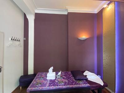 Ein Raum mit lila und gold gestrichenen Wänden und einer Massagelieg darin