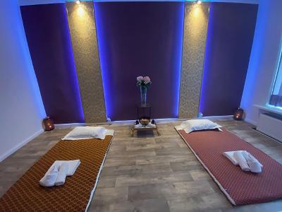 Ein Raum mit lila gestrichenen Wänden, Wandbeleuchtung und zwei Liegeunterlagen auf dem Fußboden