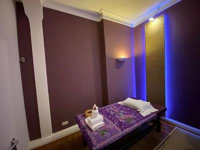 Ein Raum mit einer Wandleuchte, lilafarbenen Wänden und einem kleinen Massagetisch