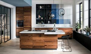Eine Küche aus Nussbaum, weißen Arbeitsflächen und blauen Wandelementen