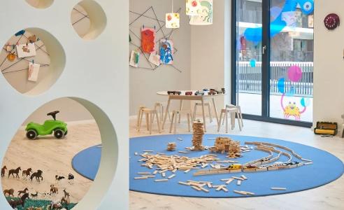 Ein heller Raum der Kita kinderzimmer Alsterberg zum spielen mit einem runden, blauen Teppich auf dem Spielzeug liegt