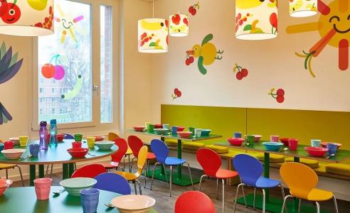 Der Raum zum essen in der Kita kinderzimmer Heidbrook, bunte Stühle und Tische mit bunten Deckenlampen