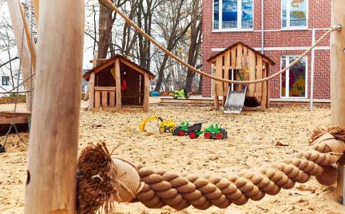 Der Spielplatz der Kita kinderzimmer Heidbrook, viel Sand und kleine Holzhäuschen