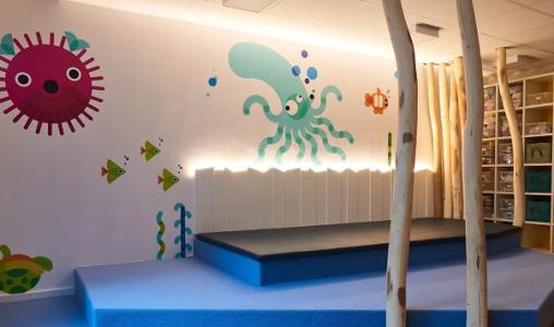 Ein Raum mit blauem Teppichboden, bunten Tieren an der Wand und einem weißen Zaun mit Hintergrundbeleuchtung