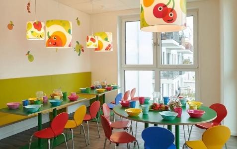 Der Raum zum Essen in der Kita kinderzimmer Süderfeldpark, bunte Stühle stehen an bunten Tischen