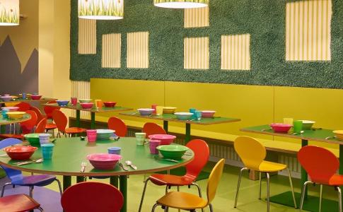 Der Raum zum Essen in der Kita kinderzimmer Valentinshof, bunte Stühle stehen an bunten Tischen und bunte Lampen hängen von der Decke