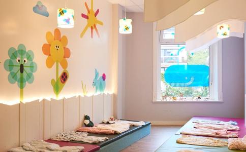 Der Bereich zum schlafen in der Kita kinderzimmer Villa Flottbek, bunte Blumen und eine Sonne wurden an die Wand gemalt, davor liegen Matten und kleine Decken zum schlafen