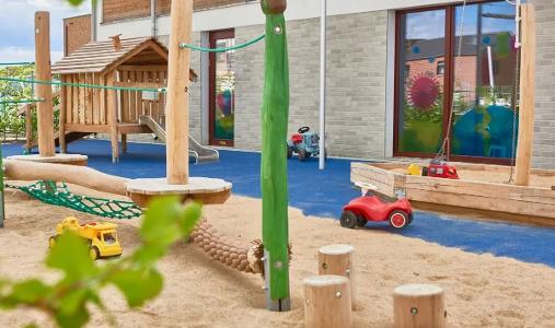 Der Spielplatz in der Kita kinderzimmer Vogelkamp, mit Holzhäuschen und Sand zum spielen