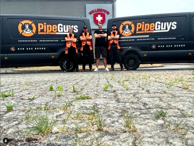 Zwei Transporter mit PipeGuys Logo und vier Männer stehen davor