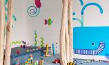 Spielzimmer der Kita kinderzimmer City Süd mit einem blauen Wal und bunten Fischen an der Wand