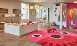 Ein großer Raum der Kita kinderzimmer Heidbrook zum spielen, mit einem Kaufmannsladen und einem großen runden Teppich mit Augen und Nase